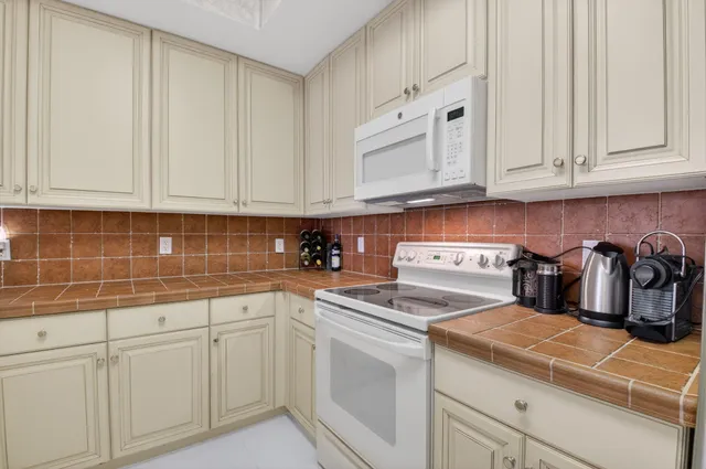 a kitchen with stainless steel appliances granite countertop white cabinets and a sink