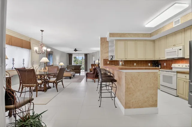 a kitchen with stainless steel appliances kitchen island granite countertop a table chairs sink and cabinets