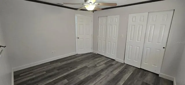 a view of an empty room with chandelier fan and closet area