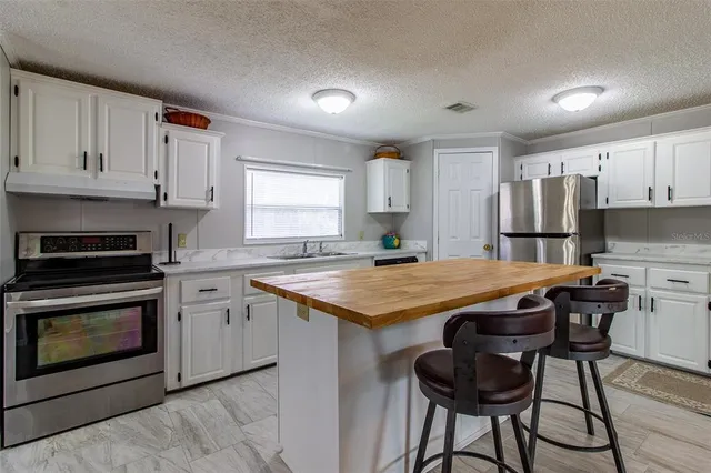 a kitchen with granite countertop a stove a sink and a refrigerator