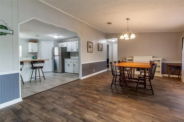 a view of a dining room and livingroom with furniture wooden floor a rug a painting and a chandelier