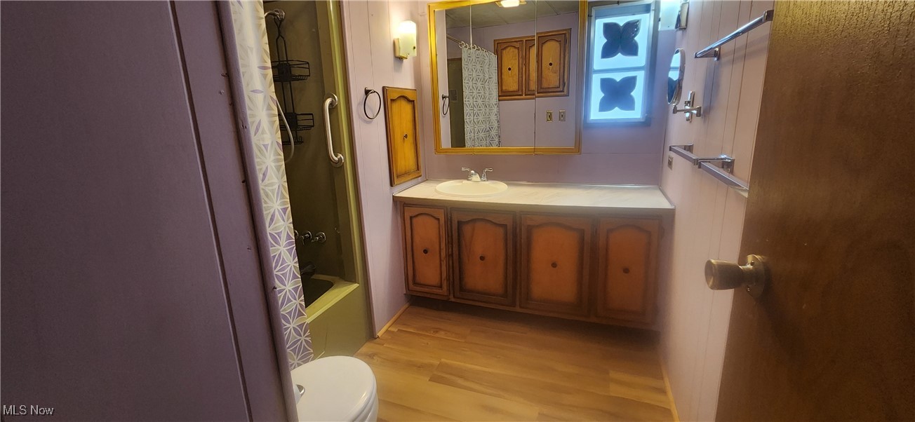 202 West Main Road, Unit 111 Conneaut, OH 44030 - Photo 26 of 27 Full bathroom featuring shower / bathtub combination with curtain, vanity, wood-type flooring, and toilet
