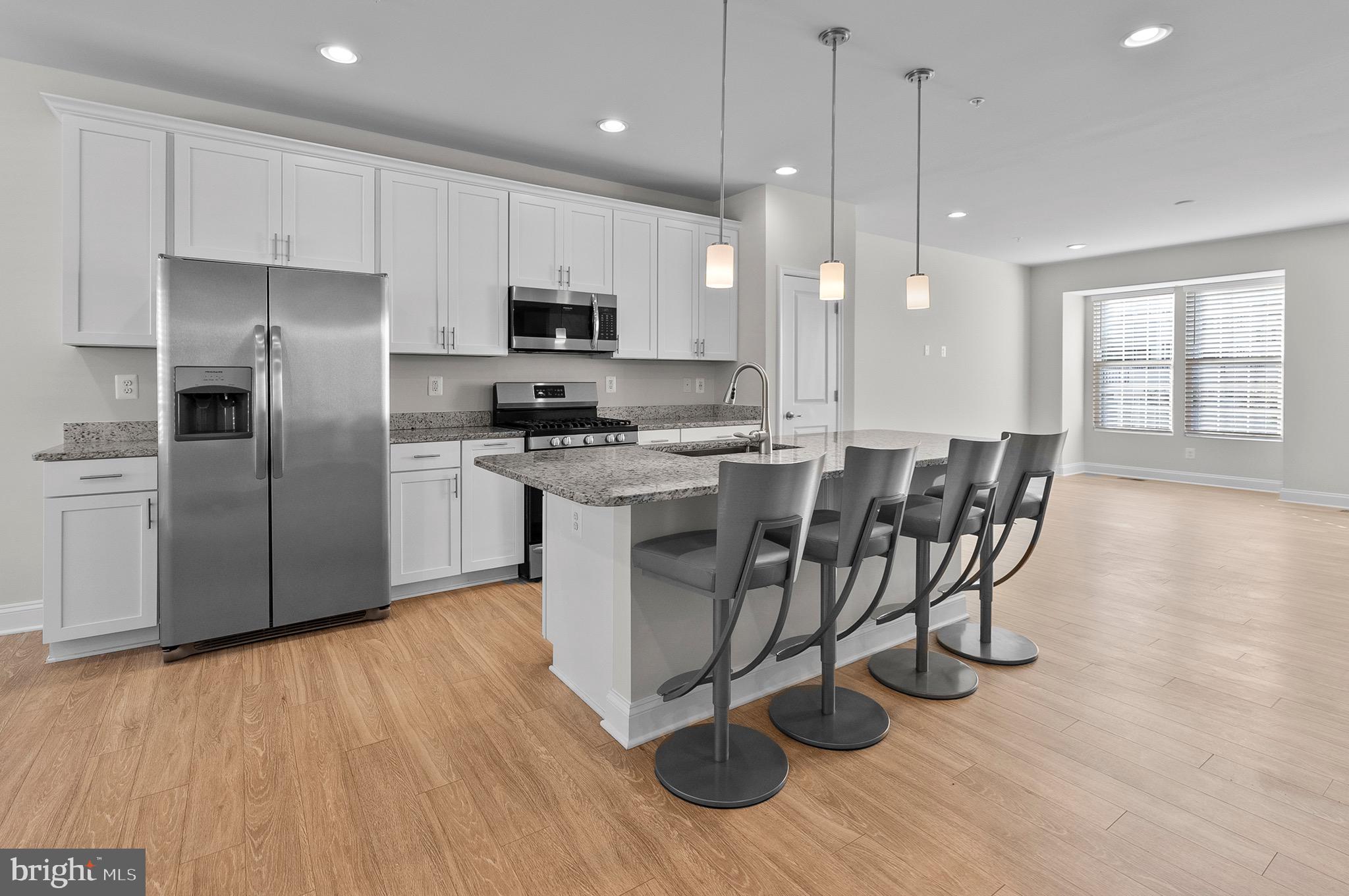 534 Calvert Way Aberdeen, MD 21001 - Photo 5 of 26 a kitchen with stainless steel appliances granite countertop a table chairs refrigerator and microwave