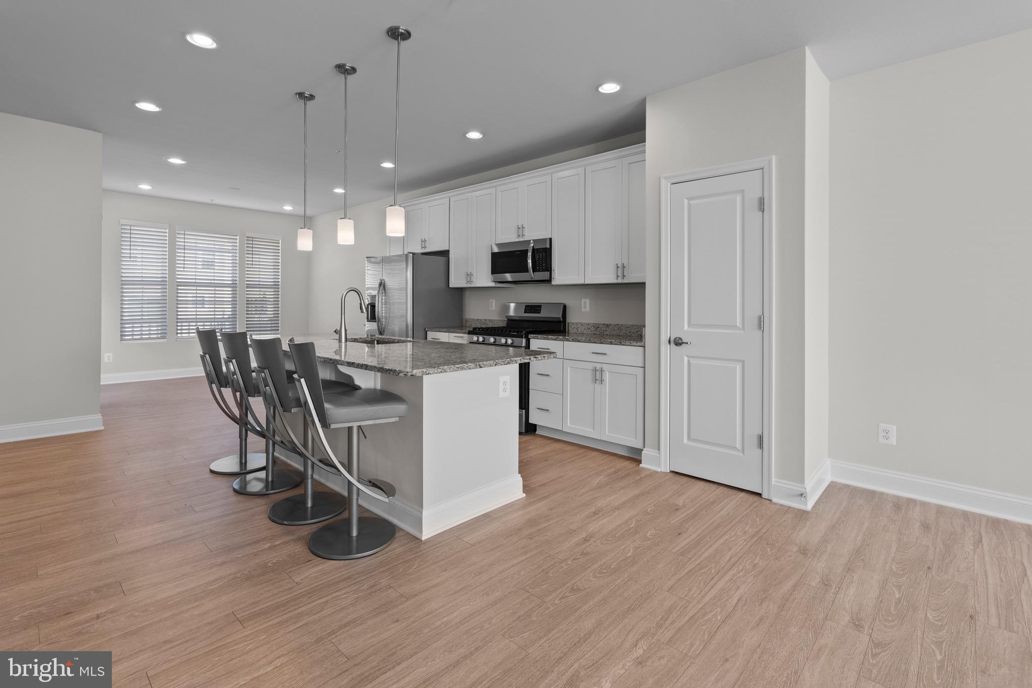 534 Calvert Way Aberdeen, MD 21001 - Photo 8 of 26 a kitchen with stainless steel appliances kitchen island granite countertop a stove top oven a sink a refrigerator with white cabinets and wooden floor