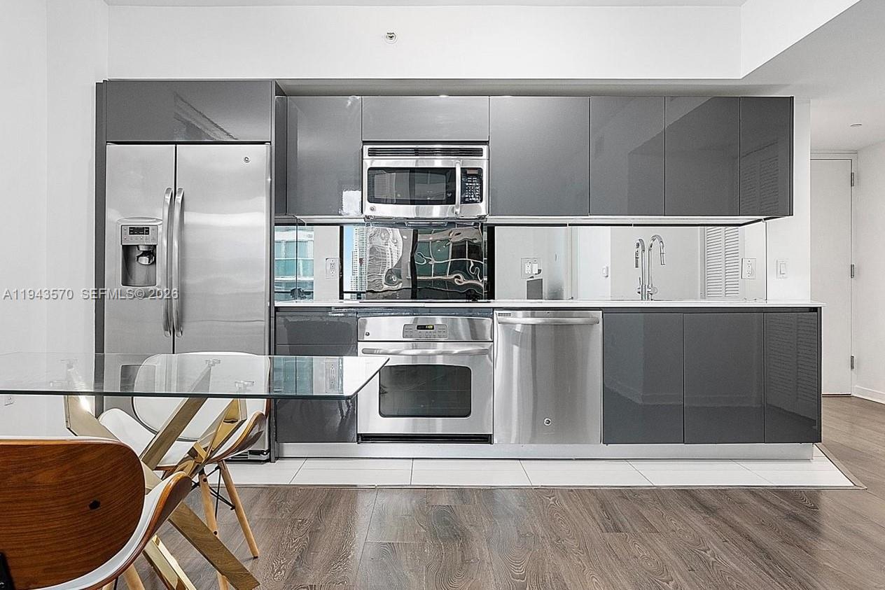 31 Southeast 6th Street, Unit 2008 Miami, FL 33131 - Photo 6 of 21 a kitchen with stainless steel appliances granite countertop a refrigerator a stove and a sink with wooden floor