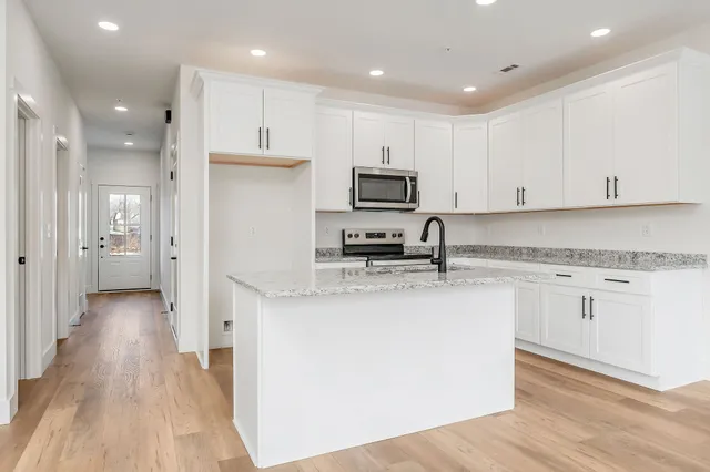 a kitchen with stainless steel appliances granite countertop a sink a stove a refrigerator and cabinets