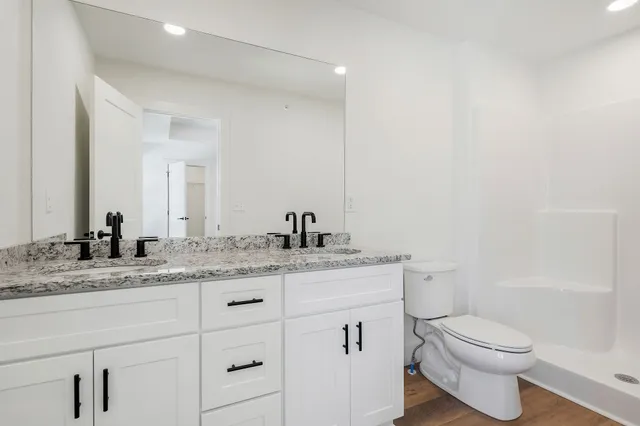 a bathroom with a granite countertop sink toilet and shower