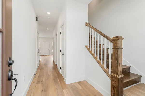 a view of a hallway with wooden floor and staircase