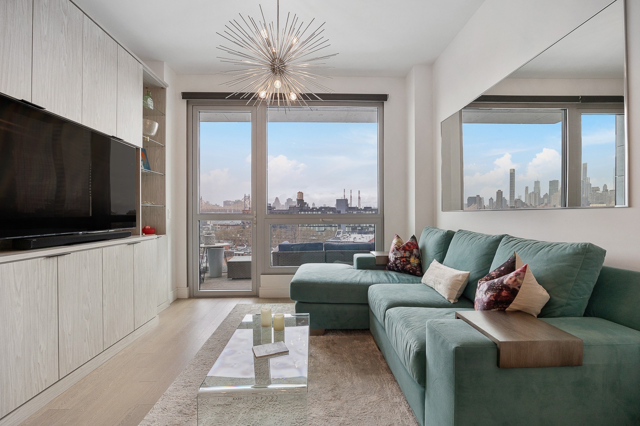 22-43 Jackson Avenue, Unit 8D Queens, NY 11101 - Photo 4 of 16 a living room with furniture a flat screen tv and a large window