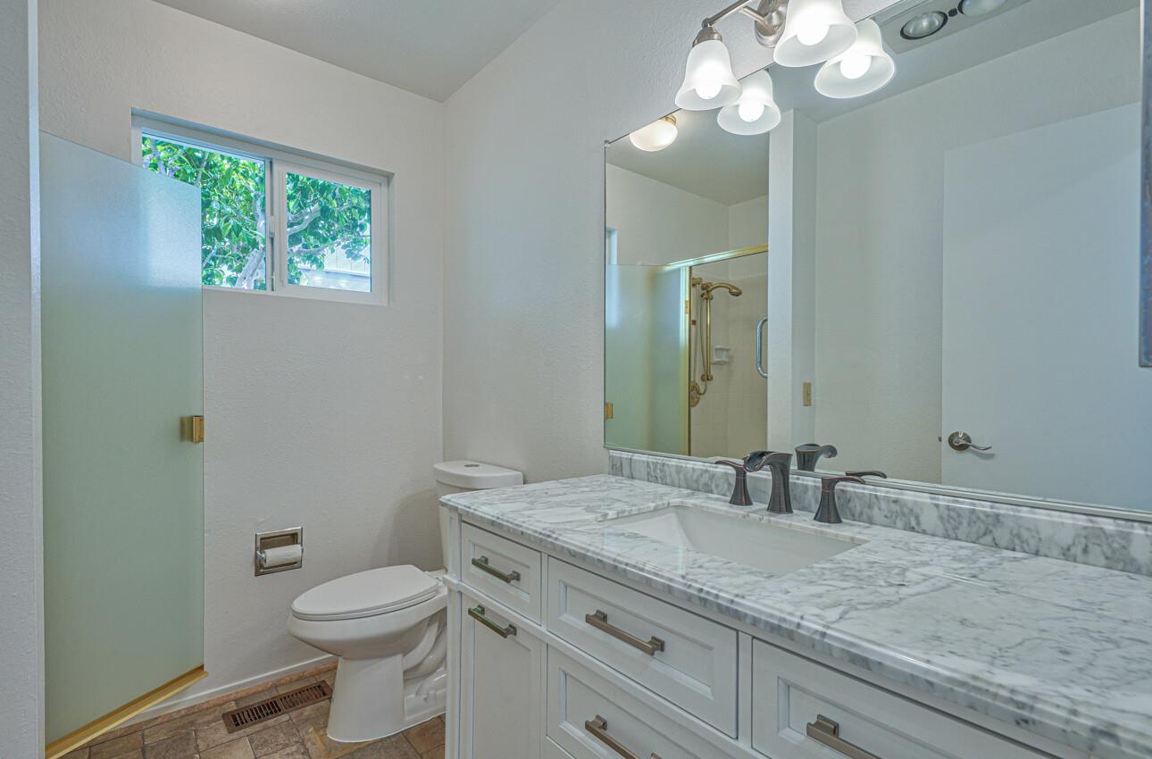 3850 Rio Road, Unit 51 Carmel, CA 93923 - Photo 9 of 24 a bathroom with a granite countertop sink a toilet and a mirror