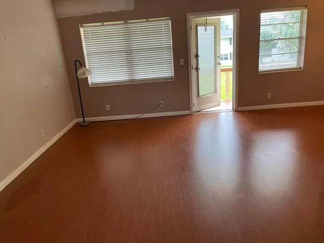 an empty room with wooden floor and windows