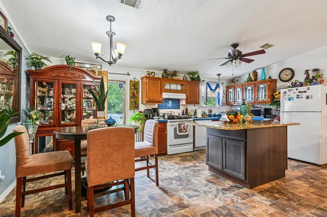 a kitchen with stainless steel appliances granite countertop a stove top oven a dining table and chairs with the living room view