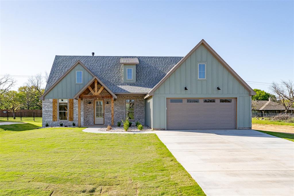 View of front of home with a garage, a front yard, board and batten siding, and a shingled roof