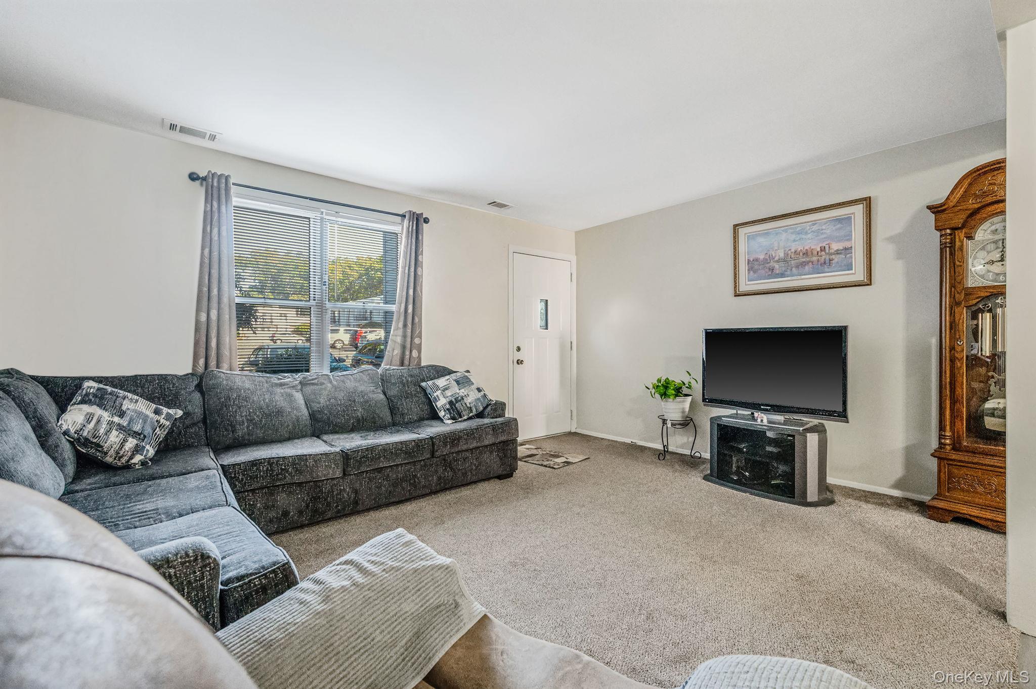 63 Rocky Point Yaphank Road, Unit 80 Rocky Point, NY 11778 - Photo 5 of 25 Carpeted living area featuring baseboards