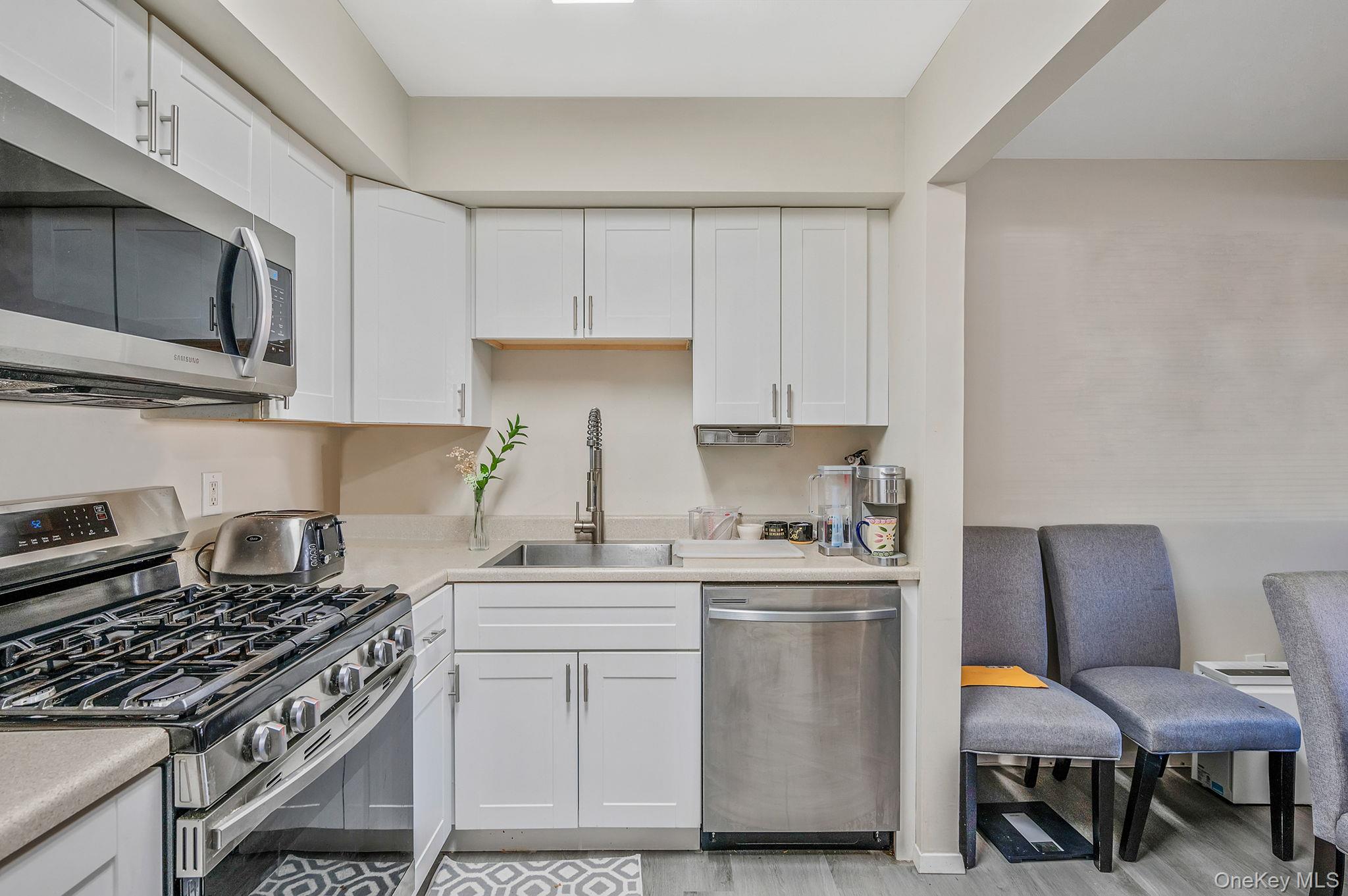 63 Rocky Point Yaphank Road, Unit 80 Rocky Point, NY 11778 - Photo 9 of 25 Kitchen with stainless steel appliances, white cabinets, light countertops, and light wood-style floors