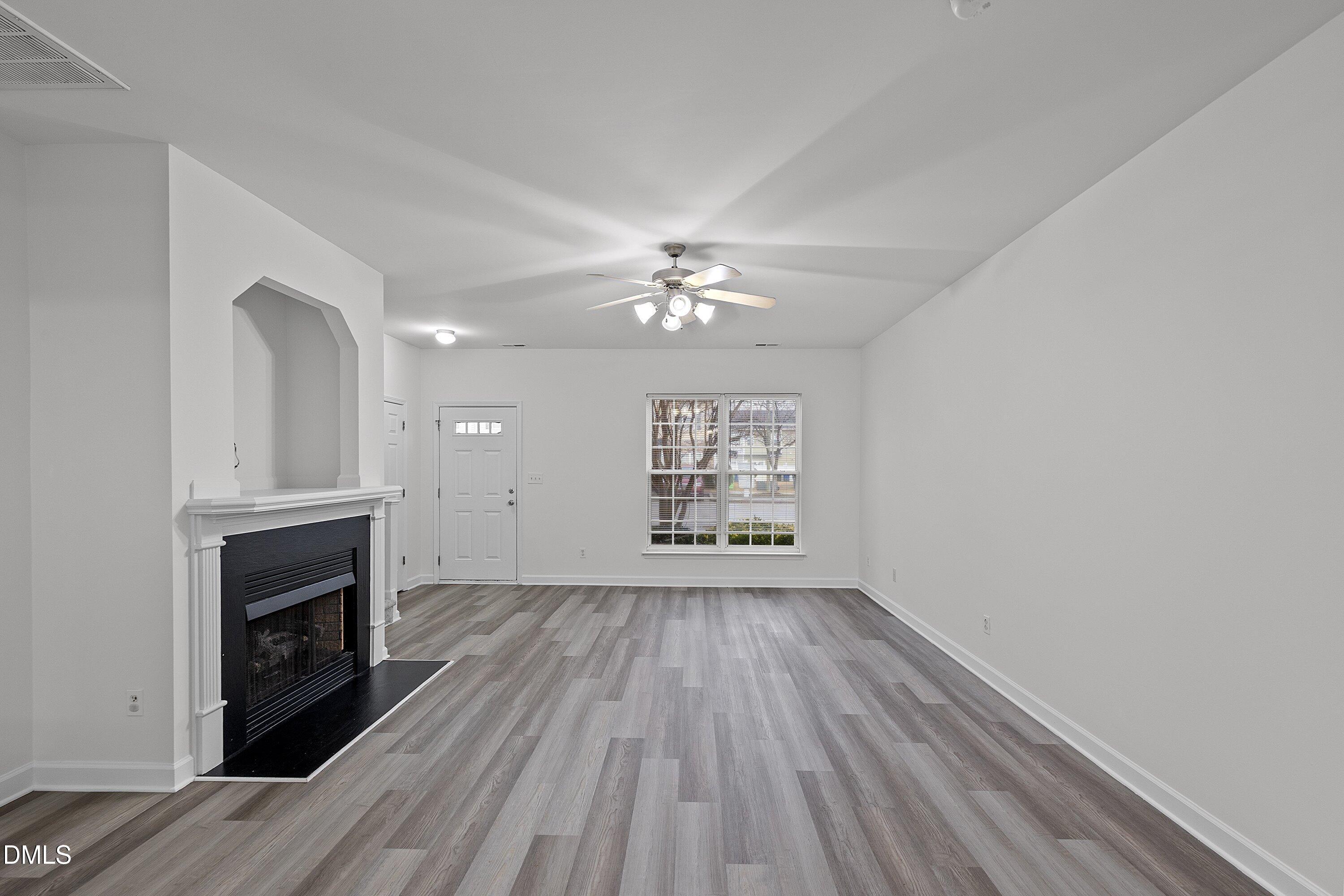 8321 Glenwood Springs Court Raleigh, NC 27616 - Photo 11 of 37 a view of an empty room with wooden floor fireplace and a window