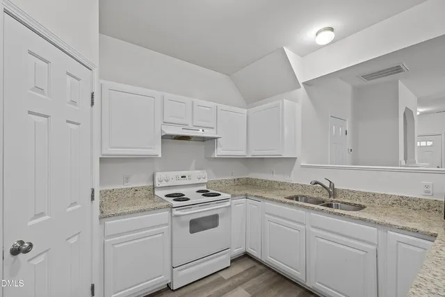 a kitchen with granite countertop white cabinets and white appliances