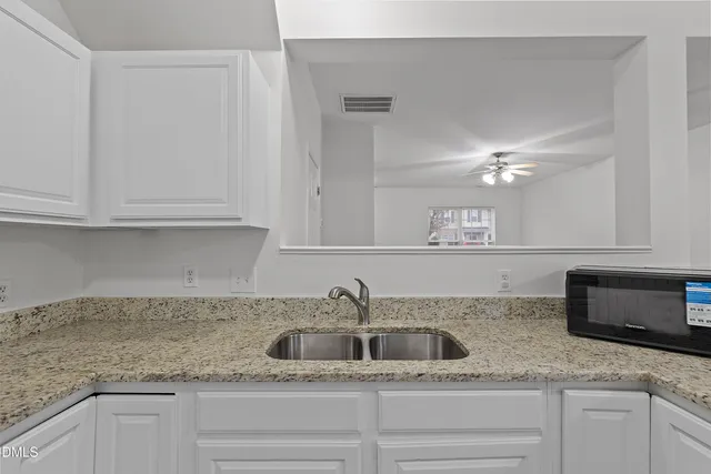 a kitchen with granite countertop white cabinets and sink