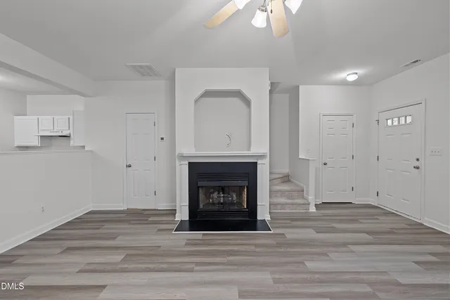 a view of an empty room with wooden floor and fireplace