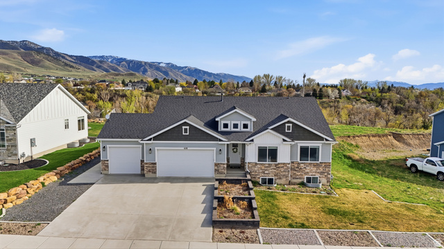 638 Canyon Rim Road Smithfield, UT 84335 - Photo 2 of 56 Craftsman-style home featuring an attached garage, stone siding, a mountain view, driveway, and a front lawn