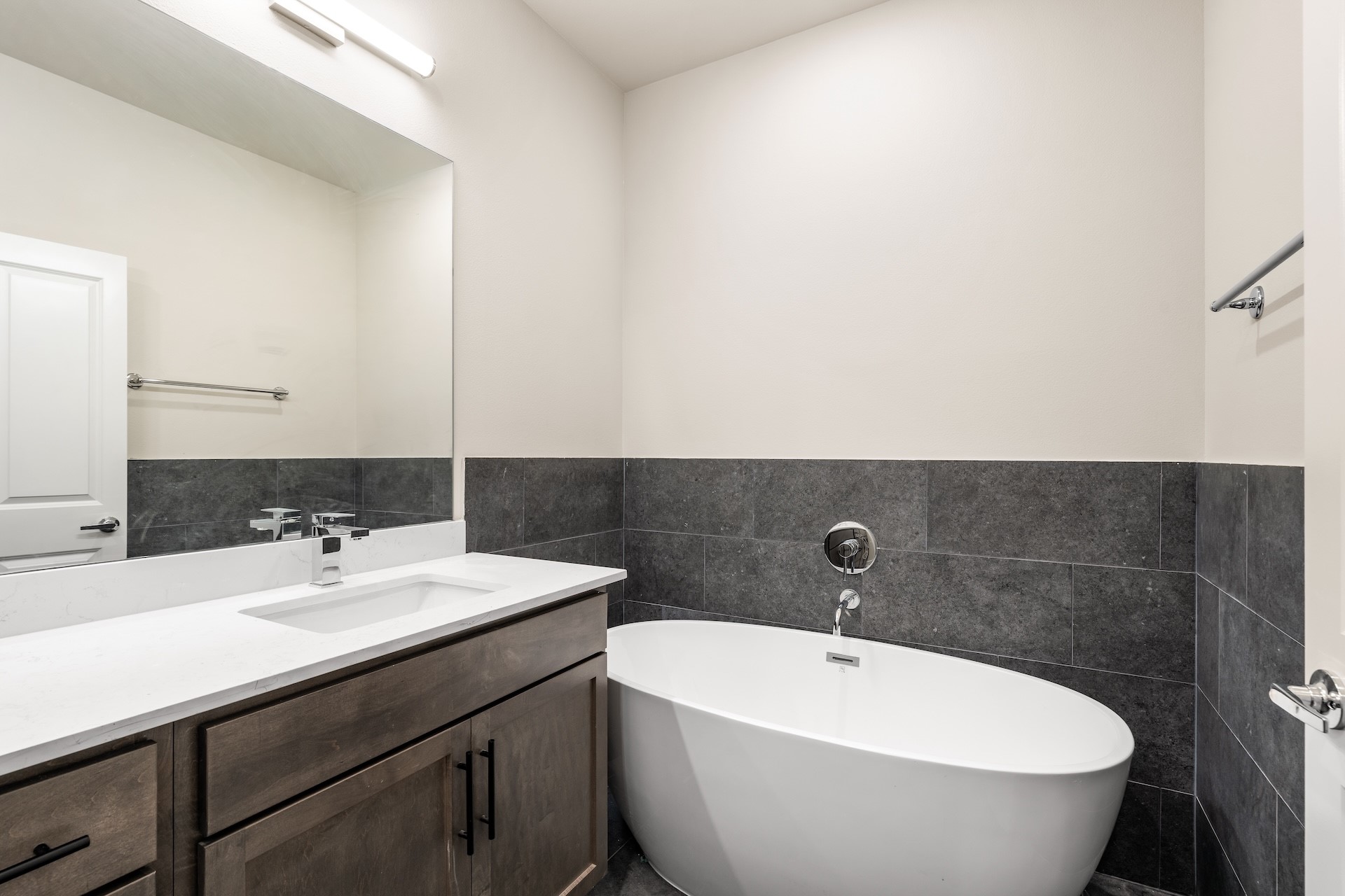6521 Rena Street Houston, TX 77092 - Photo 15 of 24 Luxurious primary bath nook — deep oval soaking tub set against dark tile surround, quartz-topped vanity, and wall-mounted tub filler.