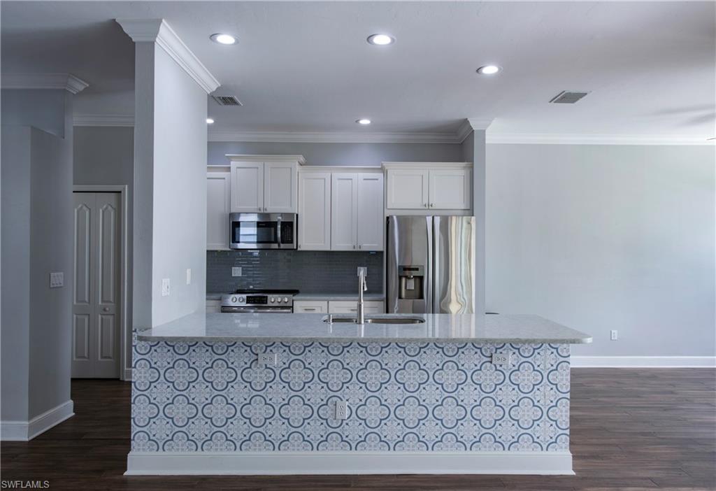 9229 Lanthorn Way Estero, FL 33928 - Photo 8 of 41 a kitchen with stainless steel appliances granite countertop a refrigerator a sink a stove with wooden cabinets