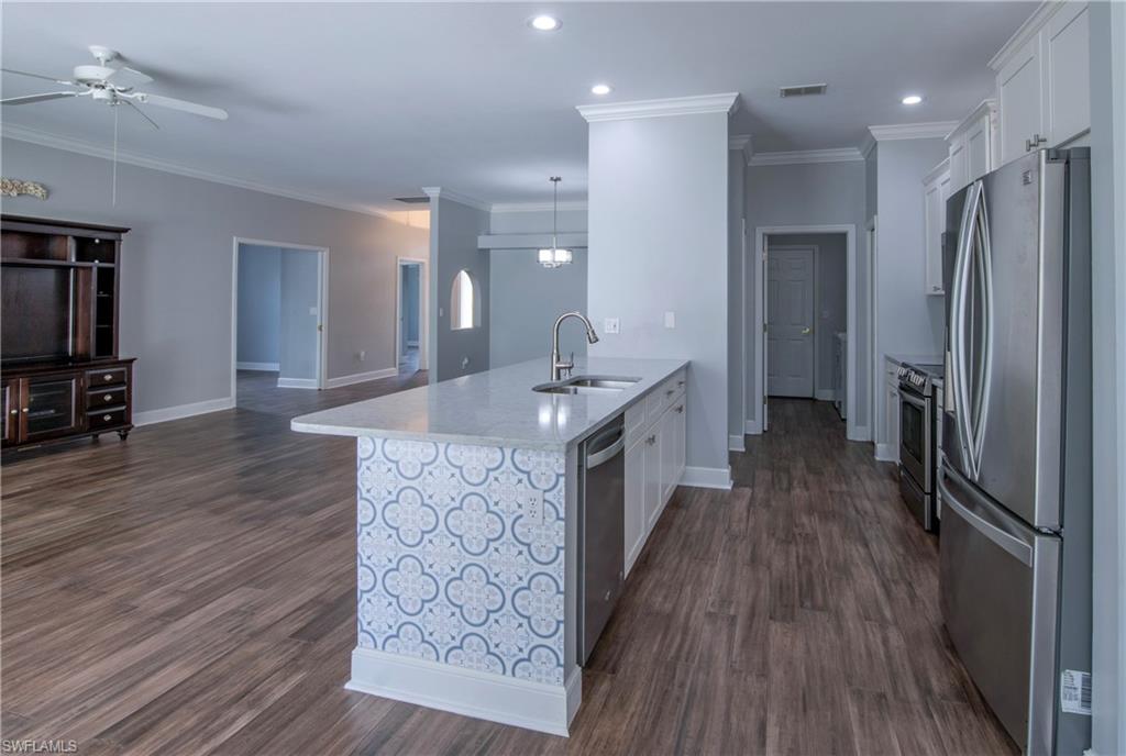 9229 Lanthorn Way Estero, FL 33928 - Photo 10 of 41 a large kitchen with stainless steel appliances a large counter top a sink and a refrigerator