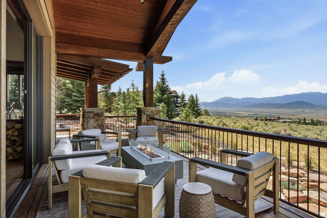 7885 North Rabbitbrush Court, Unit 13 Park City, UT 84098 - Photo 68 of 88 Expansive outdoor living area featuring a covered deck with exposed wood beams, a stone-clad fire pit, and a metal railing