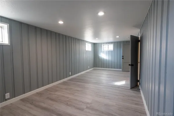 an empty room with wooden floor and windows with curtains