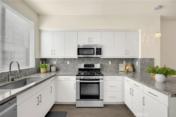 a kitchen with white cabinets white stainless steel appliances and sink