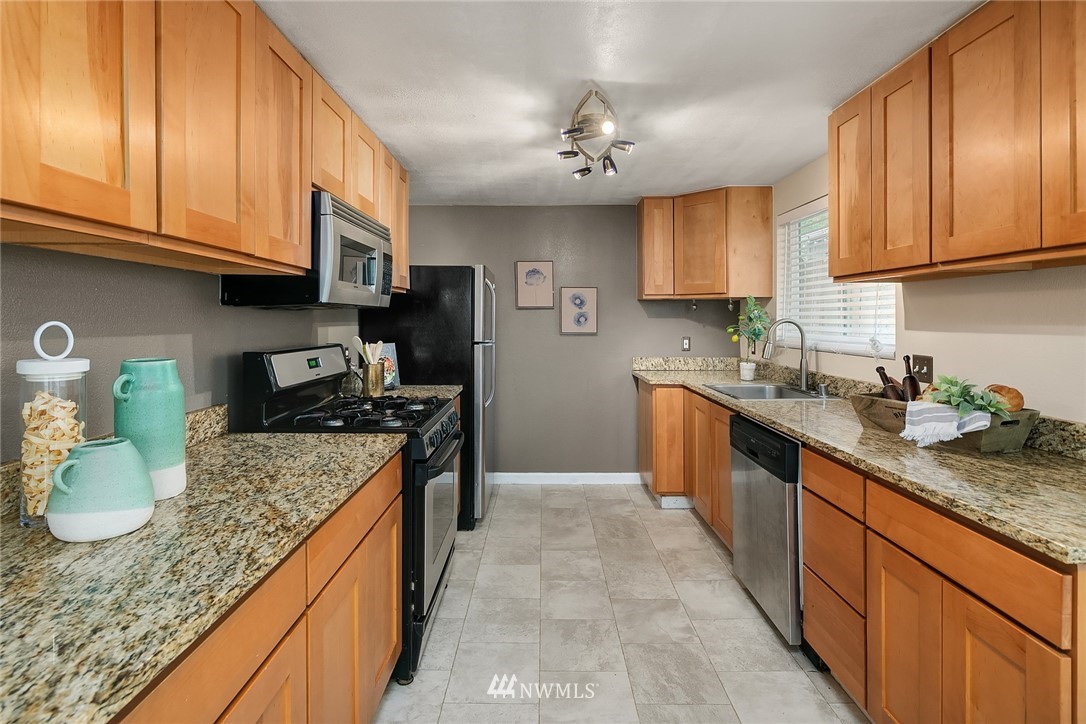 2613 Northeast 7th Street Renton, WA 98056 - Photo 8 of 23 a kitchen with granite countertop stainless steel appliances a sink a stove top oven a counter space and cabinets