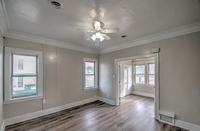 a view of an empty room with a window and wooden floor