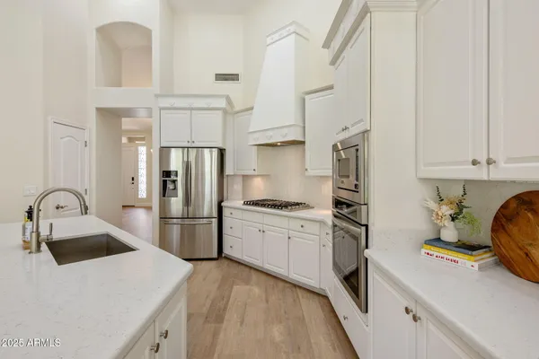 a kitchen with stainless steel appliances granite countertop a refrigerator a stove and a sink with wooden cabinets