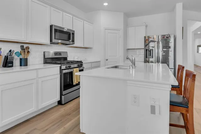 a kitchen with stainless steel appliances granite countertop a sink a stove top oven a counter space and cabinets