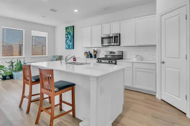 a kitchen with stainless steel appliances granite countertop a white cabinets and a stove top oven