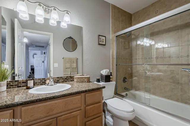 a bathroom with a granite countertop sink toilet mirror and bathtub