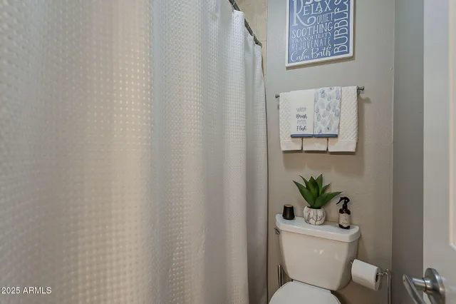 a white toilet sitting next to a white sink and curtain