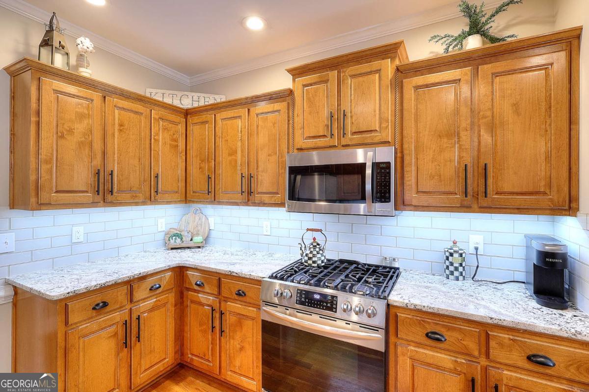 2385 Amberbrook Lane Grayson, GA 30017 - Photo 10 of 57 a kitchen with granite countertop a sink stainless steel appliances wooden floor and cabinets