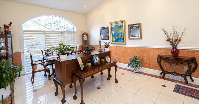 a view of a dining room and livingroom with furniture wooden floor a rug a painting and a chandelier