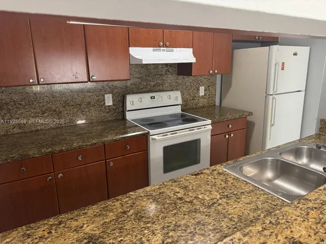 a kitchen with granite countertop a sink stainless steel appliances and cabinets