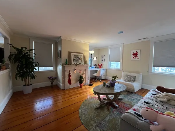 a living room with furniture and a gym machine with wooden floor