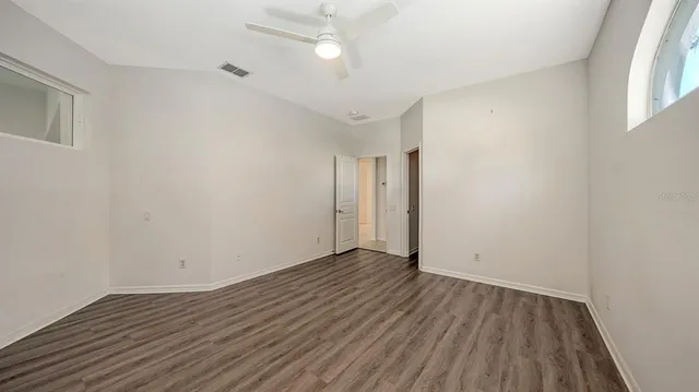 an empty room with wooden floor and windows