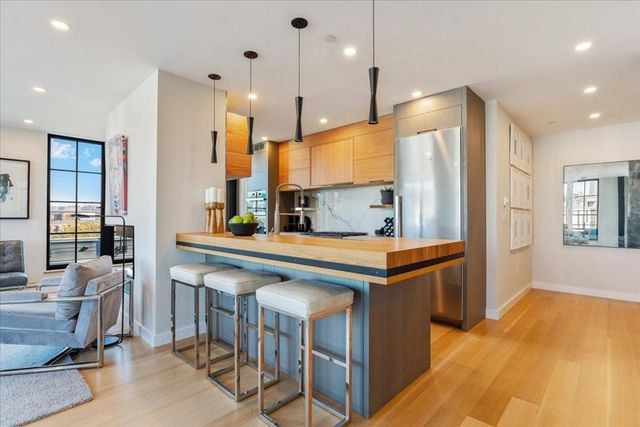 a kitchen with stainless steel appliances granite countertop a table chairs and a refrigerator
