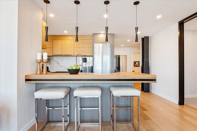 a kitchen with a sink a counter space chairs and a refrigerator