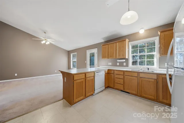 a large kitchen with kitchen island granite countertop a sink and dishwasher wooden cabinets with granite countertops