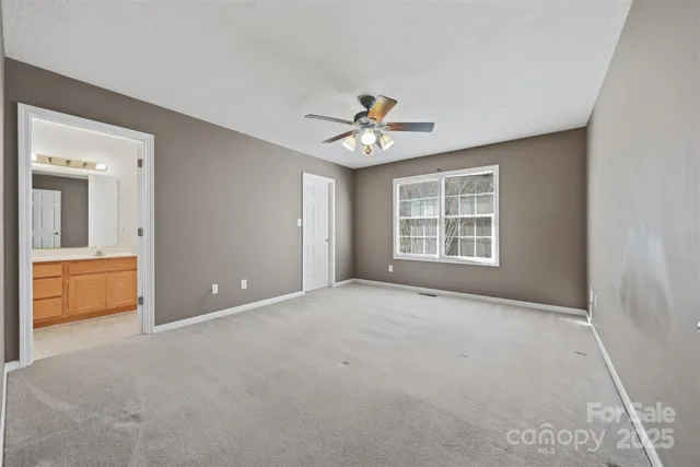 an empty room with chandelier fan and windows