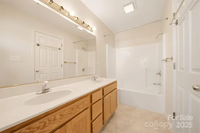 a bathroom with a sink double vanity granite tub shower and a mirror