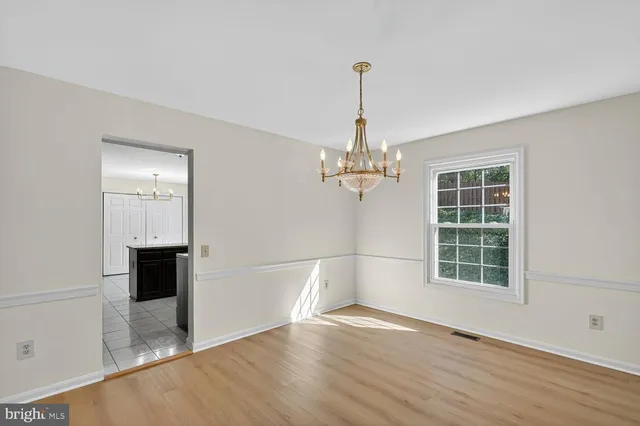 a view of a room with wooden floor chandeliers and kitchen view