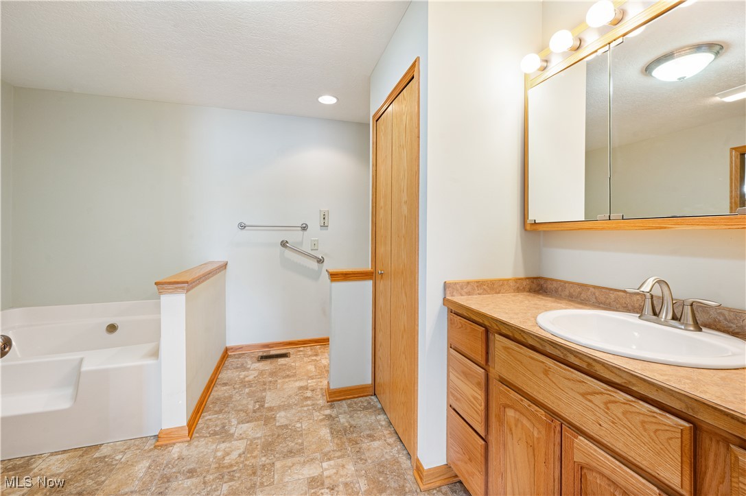 706 Watson Road Deerfield, OH 44411 - Photo 15 of 36 Bathroom with vanity, a textured ceiling, and a bathing tub