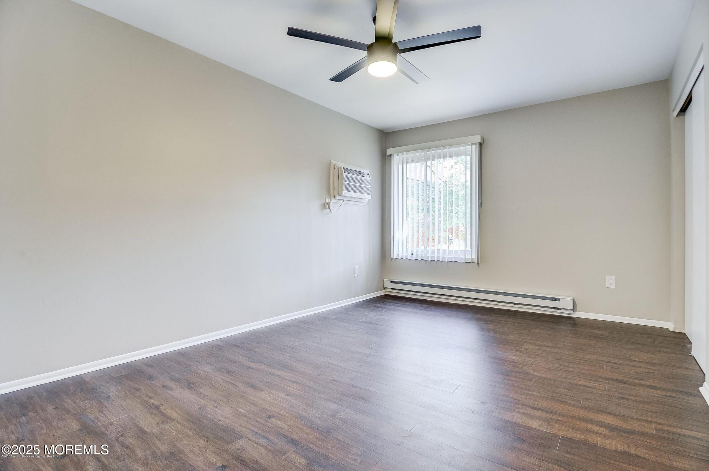 97 Arrowood Road, Unit K Manalapan, NJ 07726 - Photo 11 of 29 an empty room with wooden floor ceiling fan and windows